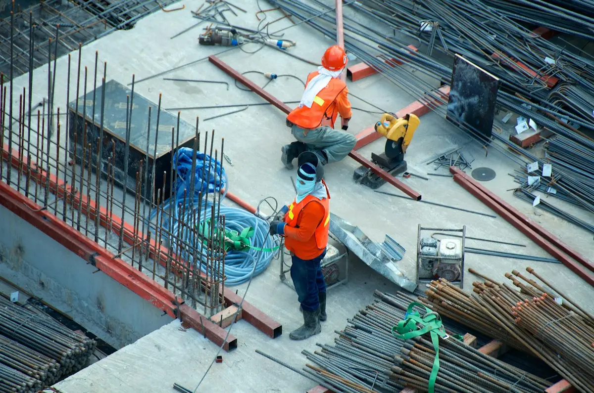 Obreros con casco y chaleco trabajando en una losa en construcción