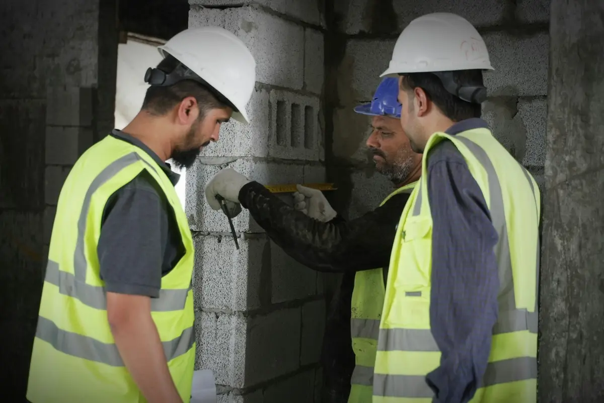 Equipo de obra con cascos y chalecos revisando un muro